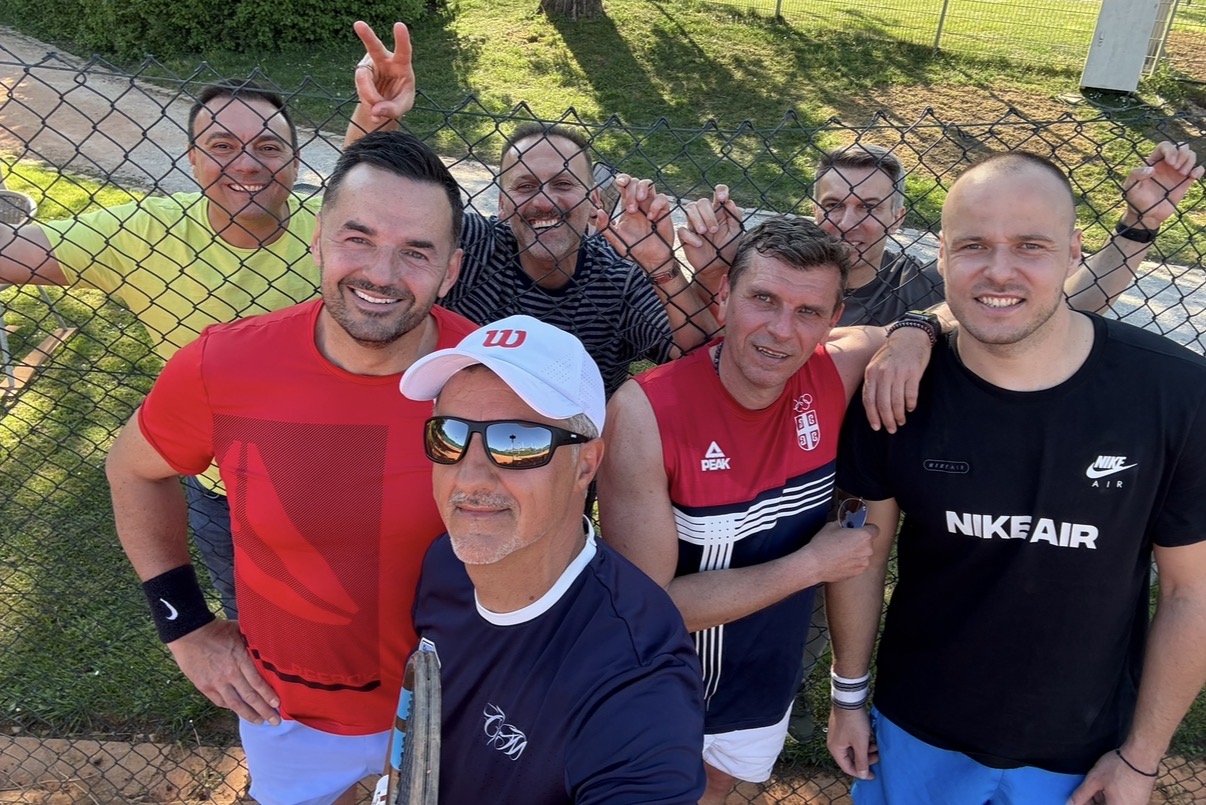 Gruppenfoto mit Trainer und Spielern am Zaun auf Sandplatz