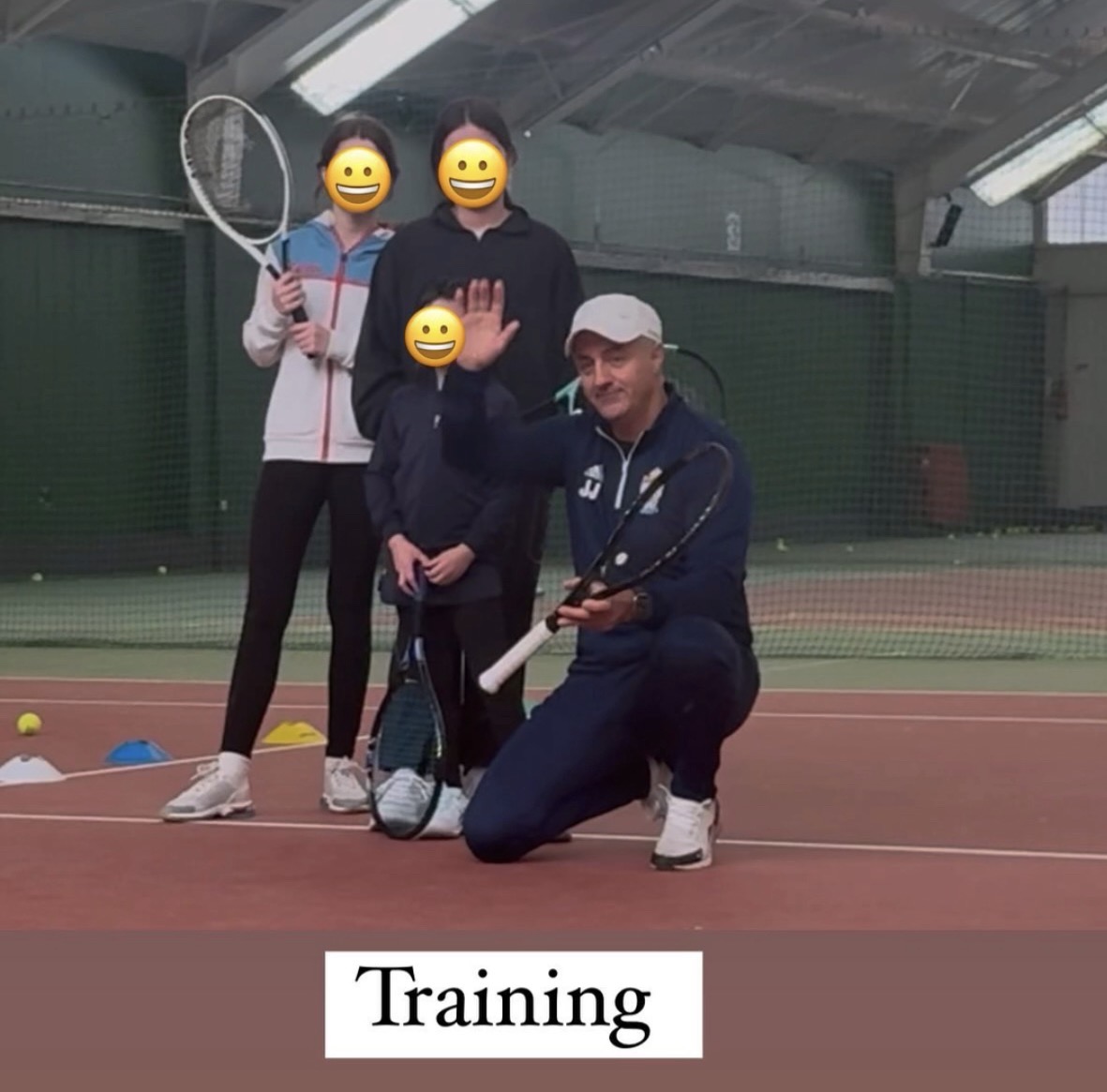 Trainer mit drei Kindern in der Tennishalle, Schläger hochgehalten