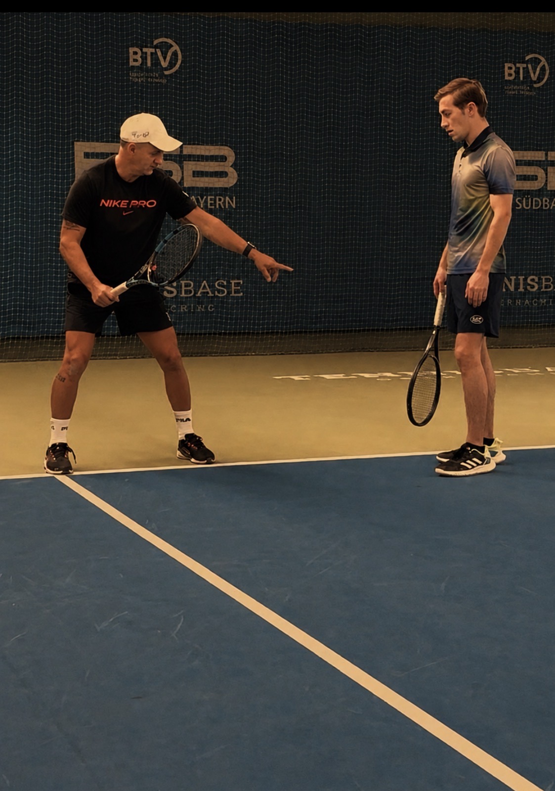 Trainer erklärt Schüler die Aufschlagposition in der TennisBase Oberhaching