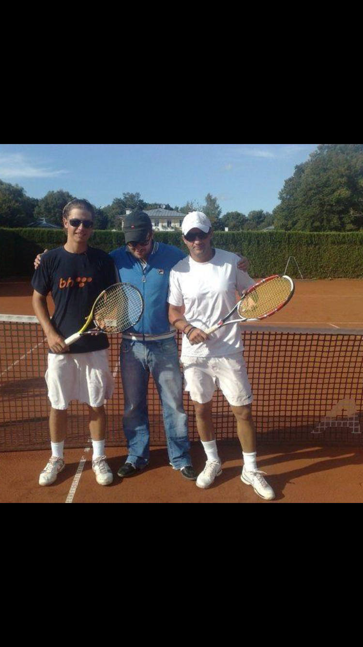 Drei Tennisspieler mit Schlägern am Netz auf Sandplatz