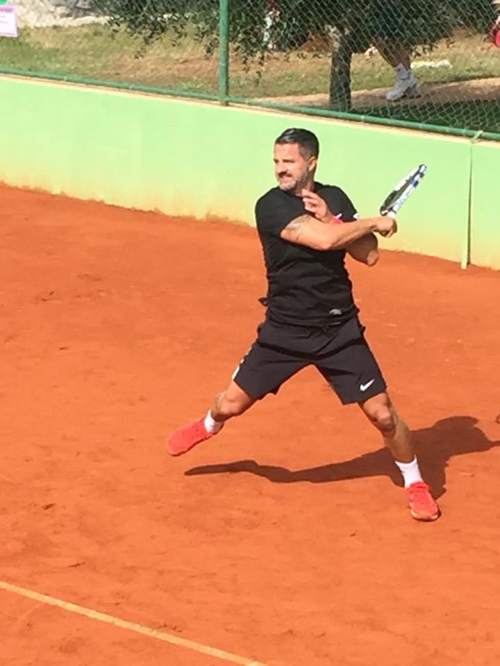 Spieler in schwarzem Trikot bei der Rückhand auf Sandplatz